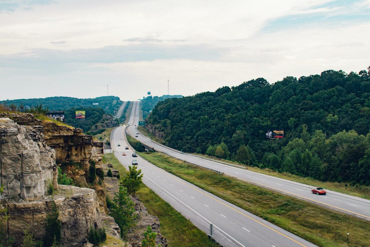 Mastering the First Impression: Your intriguing post title goes here Aerial view of a highway cutting through lush green landscapes with cliffs and signs visible.